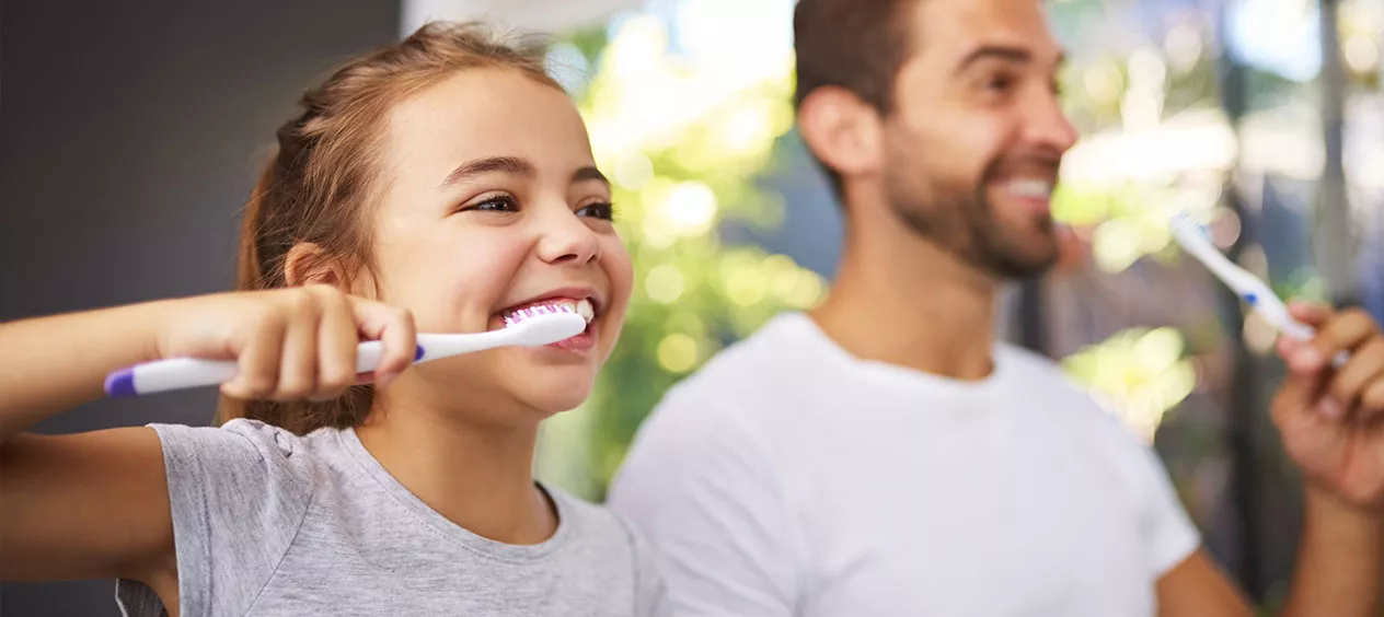 Father and daughter brushing teeth